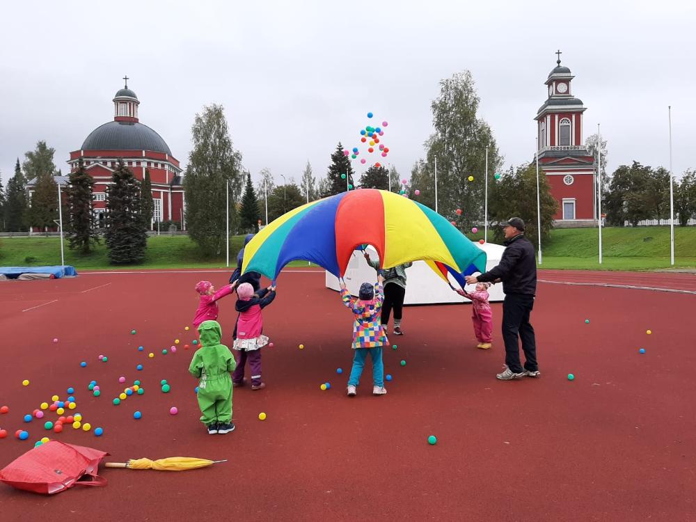 Lapsia leikkimässä värikkään varjon kanssa
