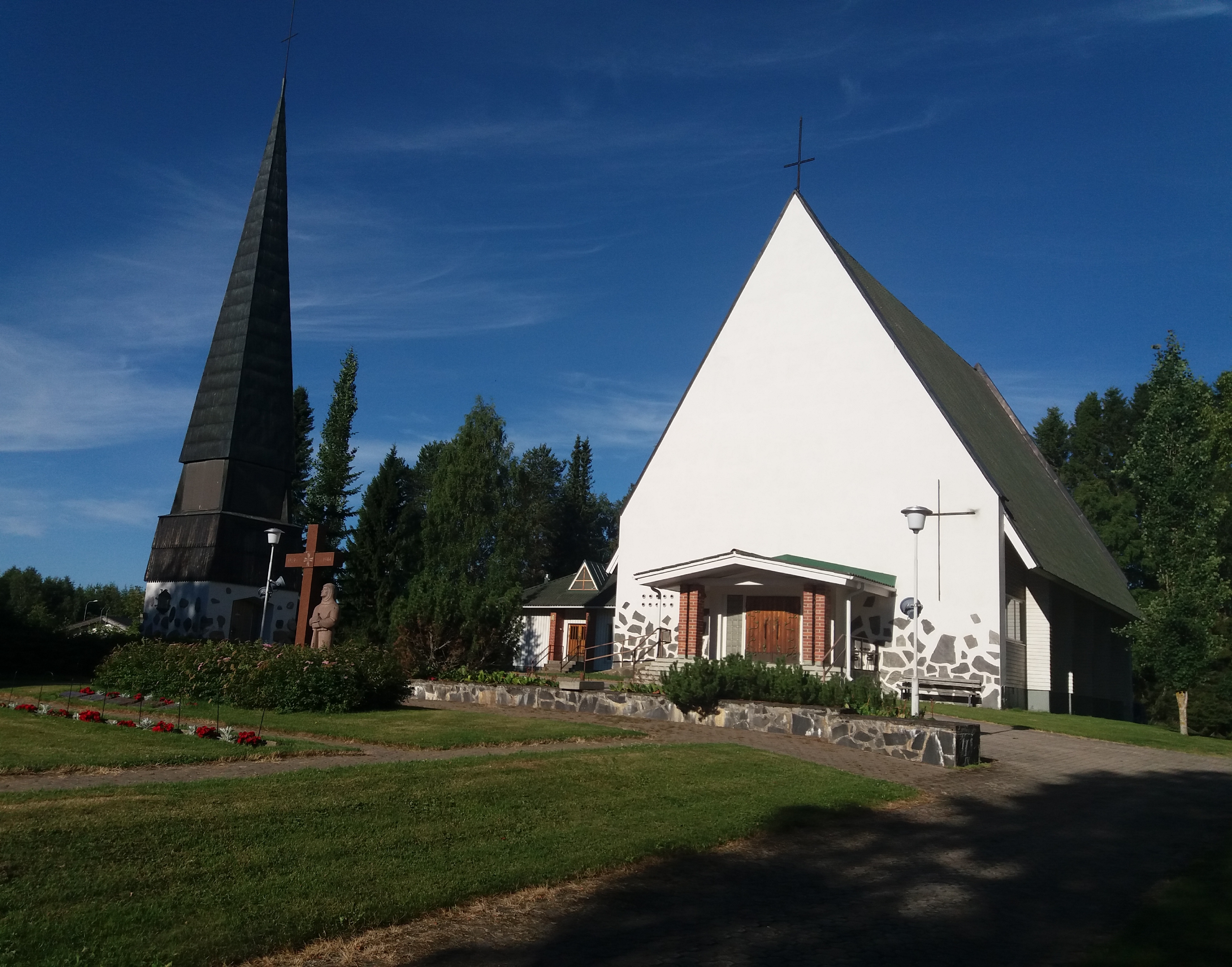 Valkoinen kirkkorakennus kesämaisemassa