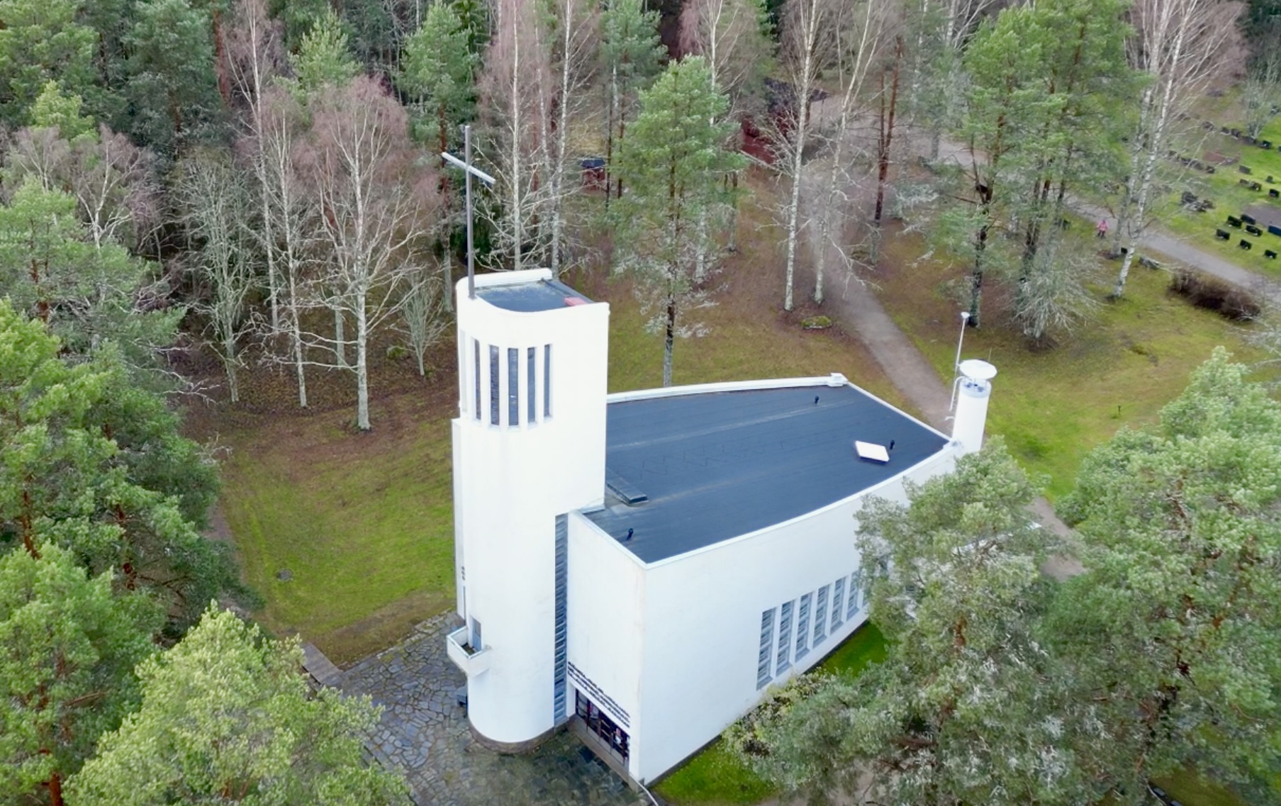valkoinen korkeatorninen kirkko havupuiden keskellä