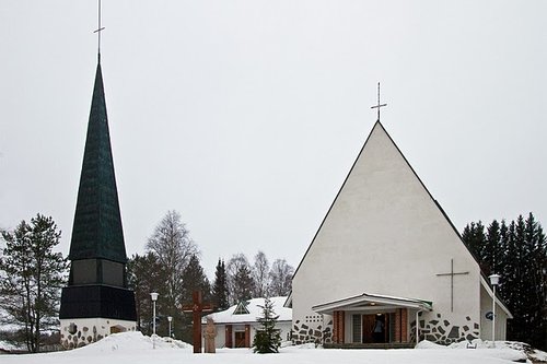 Kolmiomuotoinen kirkko, jonka vasemmalla puolella kellotorni, talvimaisemassa